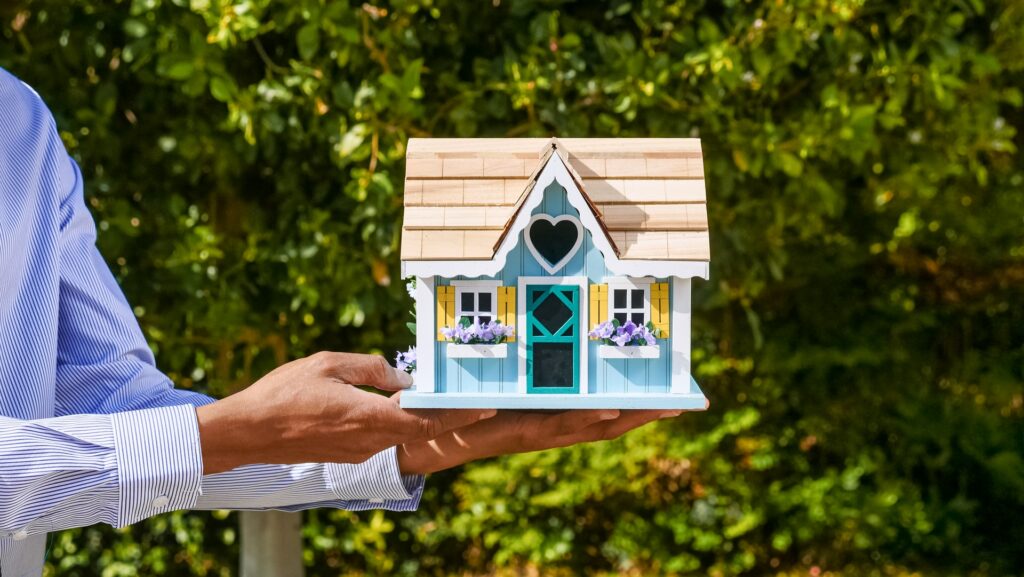 Real estate professional holding a doll house, symbolizing how easy it is to buy and sell houses with ibuyers